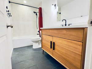 Bathroom with toilet, tile patterned floors, vanity, and washtub / shower combination