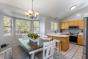 Kitchen featuring stainless steel appliances, lofted ceiling, a sink, light countertops, and a peninsula