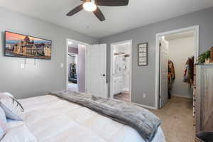 Bedroom featuring a walk in closet, a closet, light colored carpet, connected bathroom, and ceiling fan
