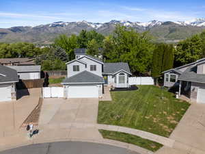 View of front facade with concrete driveway, a garage, a mountain view, stone siding, and a shingled roof