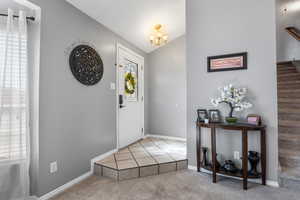 Tiled entryway with chandelier lighting, lofted ceiling, and coat closet
