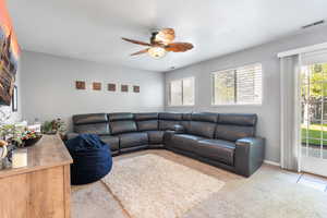 Carpeted living area featuring a ceiling fan
