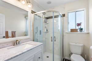 Full bathroom with a stall shower, vanity, and toilet