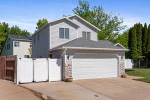 Traditional home with concrete driveway, a gate, fence, roof with shingles, and a two car garage