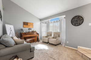 Living room with light colored carpet, bay window, and high vaulted ceiling