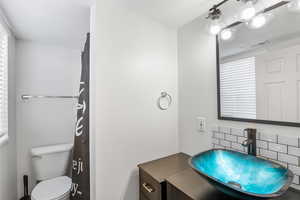 Bathroom featuring tasteful backsplash, toilet, vanity, and a textured ceiling