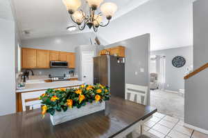 Dining area with lofted ceiling, a chandelier, light tile patterned floors, light colored carpet, and baseboards