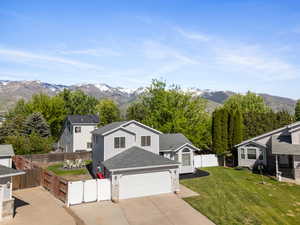 View of front of property with driveway, a mountain view, a gate, a shingled roof, and a garage
