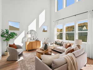 Living room with a towering ceiling, light wood finished floors, and baseboards