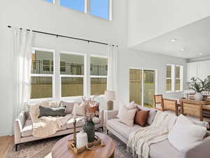 Living area with a towering ceiling, wood finished floors, and recessed lighting