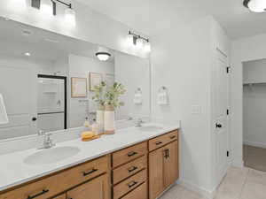 Bathroom with tile patterned floors, a stall shower, double vanity, baseboards, and a closet