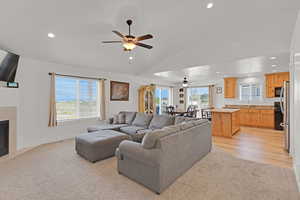 Living room with a ceiling fan, lofted ceiling, recessed lighting, a tile fireplace, and light carpet
