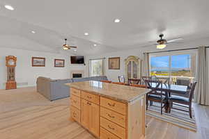 Kitchen featuring ceiling fan, light wood finished floors, light brown cabinets, a tiled fireplace, and a textured ceiling