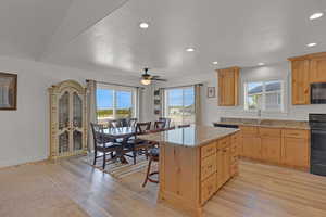 Kitchen with a sink, light brown cabinetry, range, light wood-style flooring, and a kitchen island