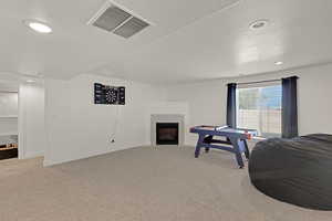 Game room with carpet floors, a tiled fireplace, a textured ceiling, recessed lighting, and baseboards