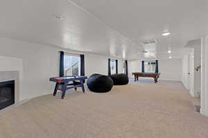 Rec room featuring light colored carpet, billiards table, recessed lighting, a tile fireplace, and baseboards