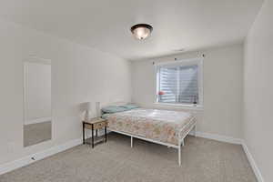 Carpeted bedroom with baseboards and a textured ceiling