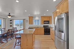 Kitchen featuring black appliances, light brown cabinetry, light wood finished floors, and recessed lighting