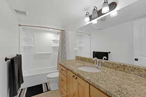 Full bathroom with tile patterned floors, toilet, shower / tub combo, and vanity