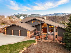 View of front of house featuring a mountain view, a shingled roof, concrete driveway, a garage, and a chimney