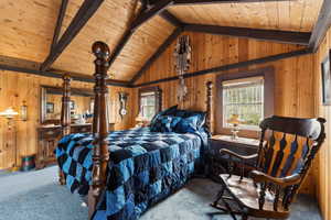 Carpeted bedroom with multiple windows, wood ceiling, and wood walls