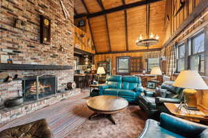 Carpeted living area with wooden ceiling, high vaulted ceiling, beamed ceiling, wooden walls, and a chandelier