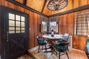 Dining room with wooden walls, a chandelier, wooden ceiling, and wood-type flooring