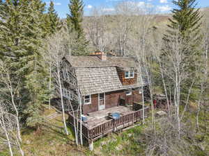 Back of house featuring a chimney and a wooden deck