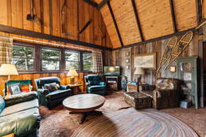 Living room featuring carpet flooring, wooden walls, high vaulted ceiling, wood ceiling, and beam ceiling