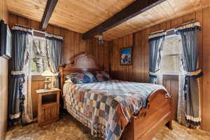 Bedroom featuring wooden ceiling, beamed ceiling, carpet floors, and wood walls