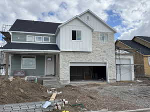 View of front facade featuring board and batten siding, an attached garage, dirt driveway, and a porch