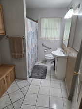 Bathroom featuring vanity, toilet, baseboards, a shower with curtain, and tile patterned floors