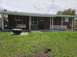 Rear view of property with a patio, a yard, and brick siding