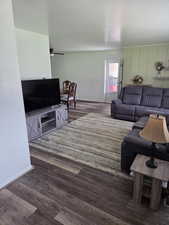 Living room with a ceiling fan, wood finished floors, and baseboards