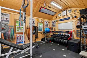 Outbuilding used as a workout room featuring vaulted ceiling, wood walls, and wooden ceiling