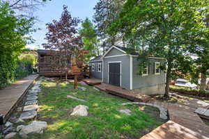 View of grassy yard featuring a deck, an outbuilding, and a storage unit