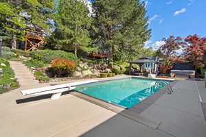 Swimming pool with a jacuzzi, a gazebo, a diving board, stairway, and a patio