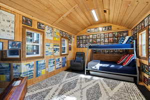 Outbuilding used as a bedroom/playroom featuring lofted ceiling, wooden ceiling,  and wood walls
