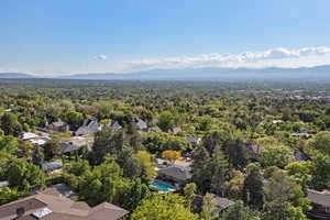 Aerial view of residential area with mountains, a heavily wooded area, and a pool area