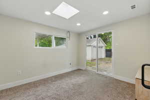 Unfurnished room featuring baseboards, carpet floors, a skylight, and recessed lighting