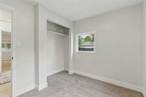 Unfurnished bedroom featuring light carpet, baseboards, and a closet