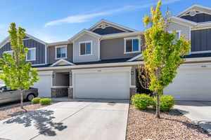 Townhome / multi-family property with board and batten siding, brick siding, a garage, and concrete driveway