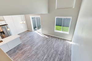 Unfurnished living room featuring wood finished floors, a chandelier, and baseboards