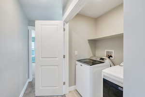 Laundry room with washer and clothes dryer and baseboards
