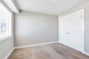 Unfurnished bedroom with carpet floors, baseboards, and a closet