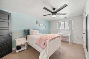 Bedroom featuring light colored carpet, a textured ceiling, a ceiling fan, and baseboards