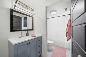 Bathroom with vanity, toilet, curtained shower, and tile patterned flooring