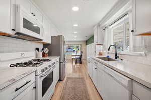 Kitchen with white appliances, a sink, recessed lighting, light wood-style flooring, and light countertops