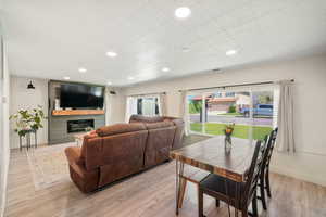 Dining area featuring light wood-style flooring, a glass covered fireplace, recessed lighting, and baseboards