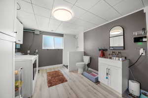 Full bathroom featuring independent washer and dryer, toilet, a shower, wood finished floors, and baseboards